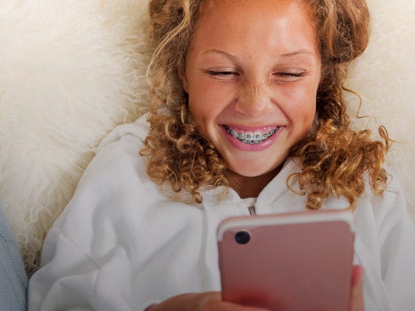 Young girl with braces laughing at her phone