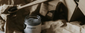 charcoal toothpaste or black powder in a jar next to a charcoal toothbrush
