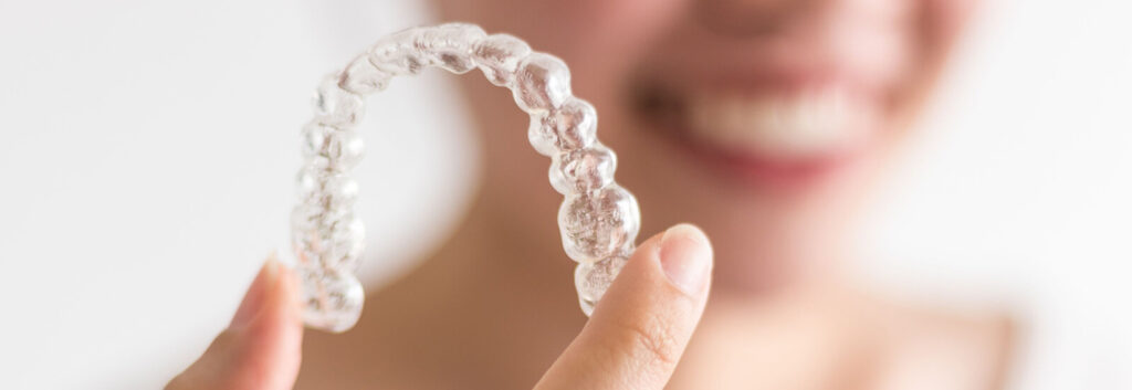 adult holds up Invisalign tray after learning Invisalign tips