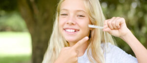 girl holds up aligner after learning Invisalign tips